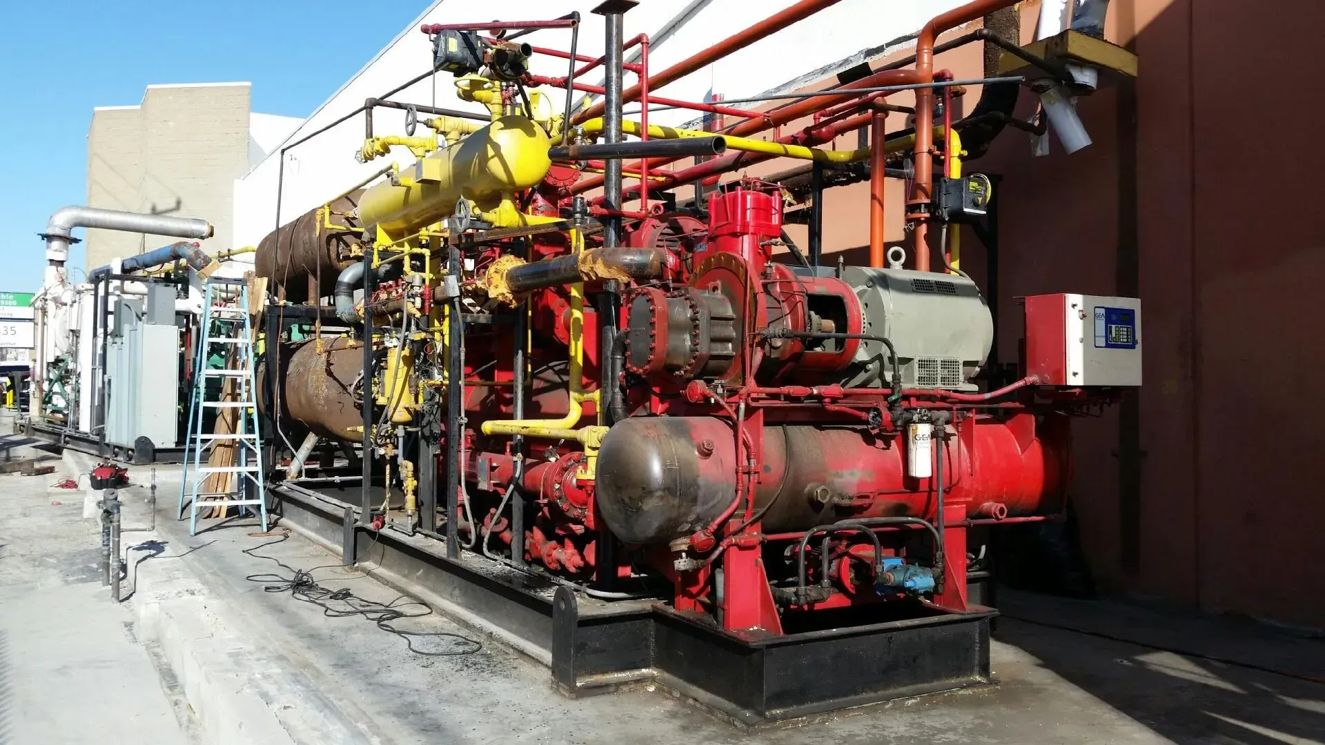A large red and yellow machine is sitting outside of a building