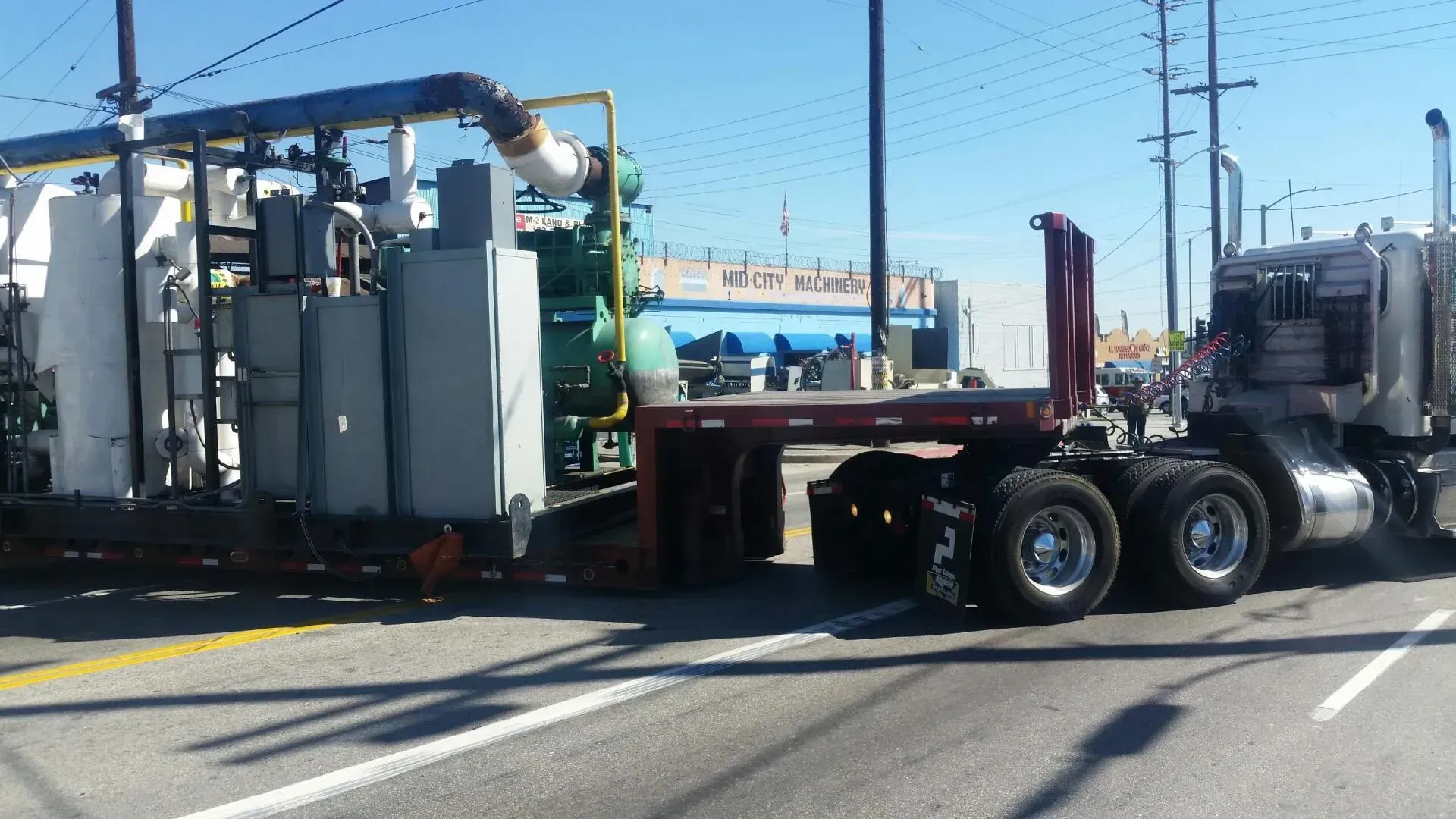 A semi truck is driving down a street with a lsu sign on the side of it