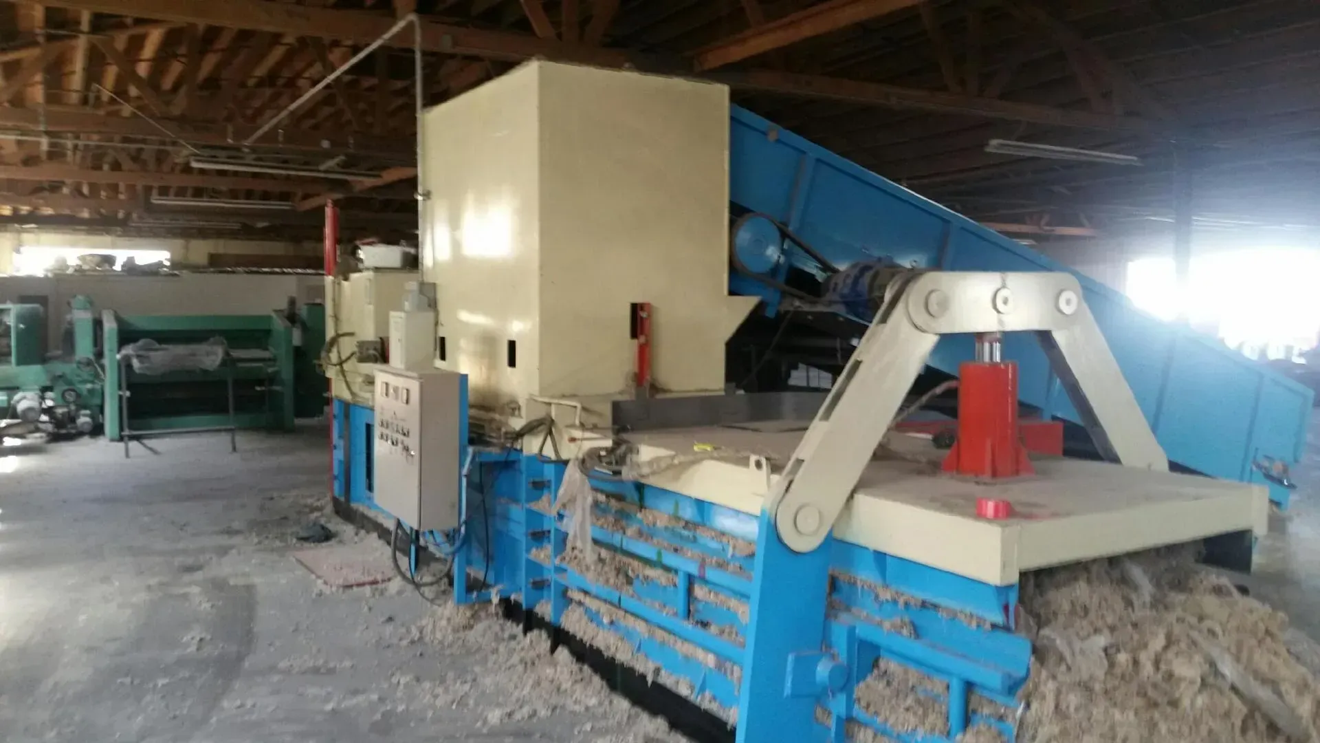 A blue and white machine is sitting in a warehouse.