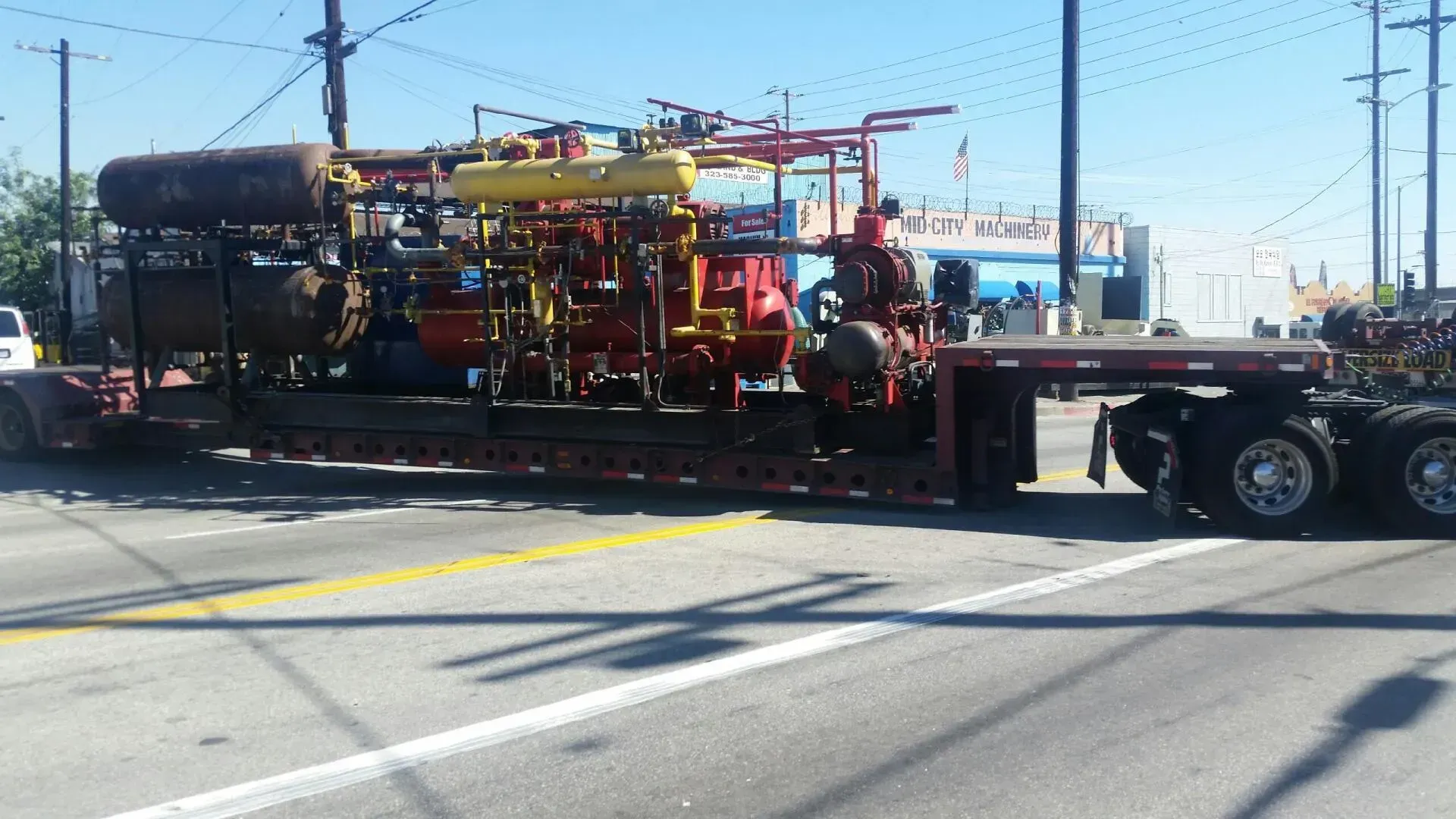 A semi truck is carrying a large piece of equipment down the road