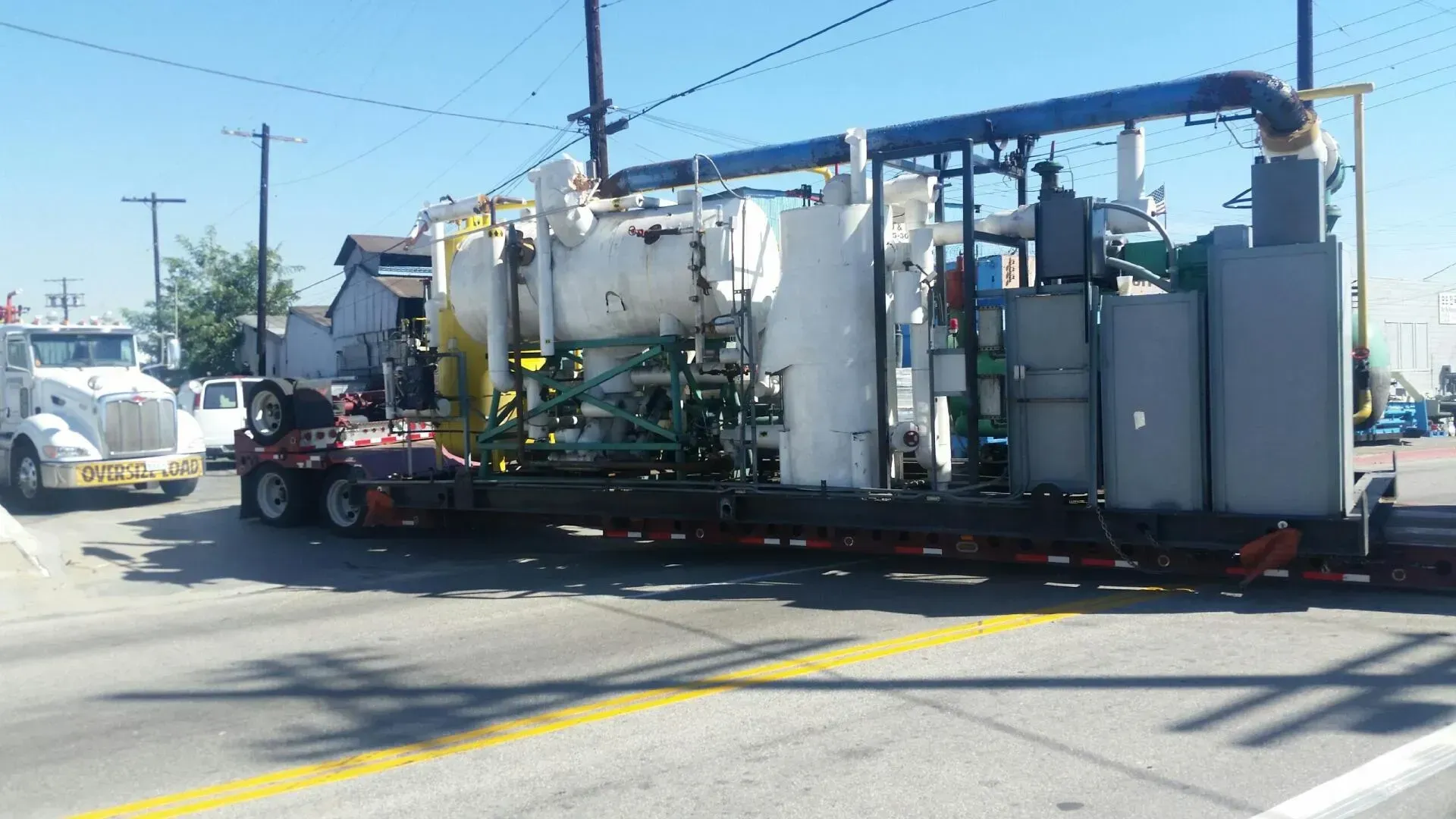 A truck is carrying a large piece of equipment on a trailer.