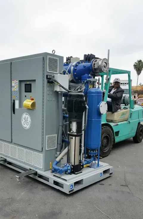 A forklift is carrying a large machine on a pallet.