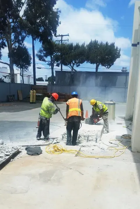 A group of construction workers are cutting concrete in a parking lot.