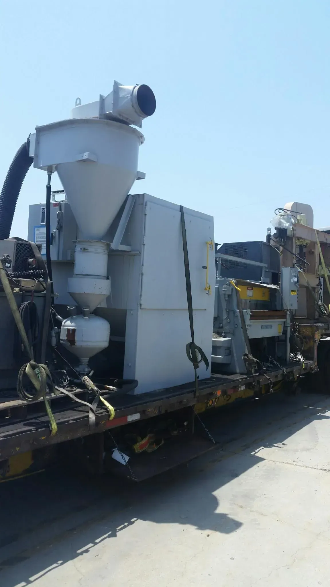 A large white machine is sitting on top of a flatbed truck.