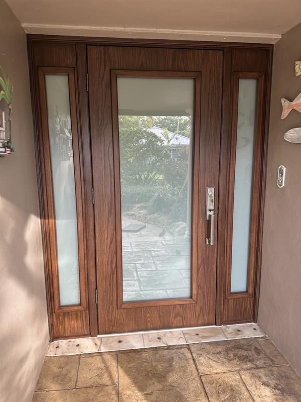 White front door with sidelight; silver hardware, beige walls, and light-colored floor.