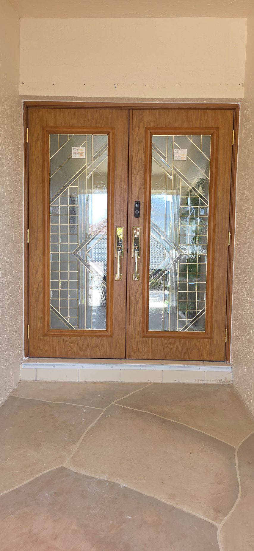 Double wooden front doors with glass insets; stone entryway.