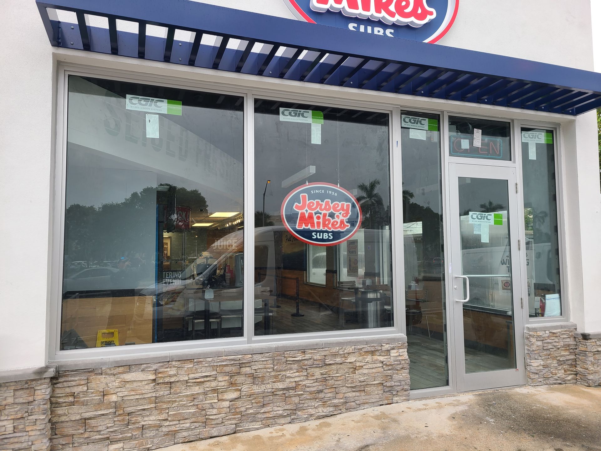 Exterior of a Jersey Mike's shop with large windows and a sign visible.