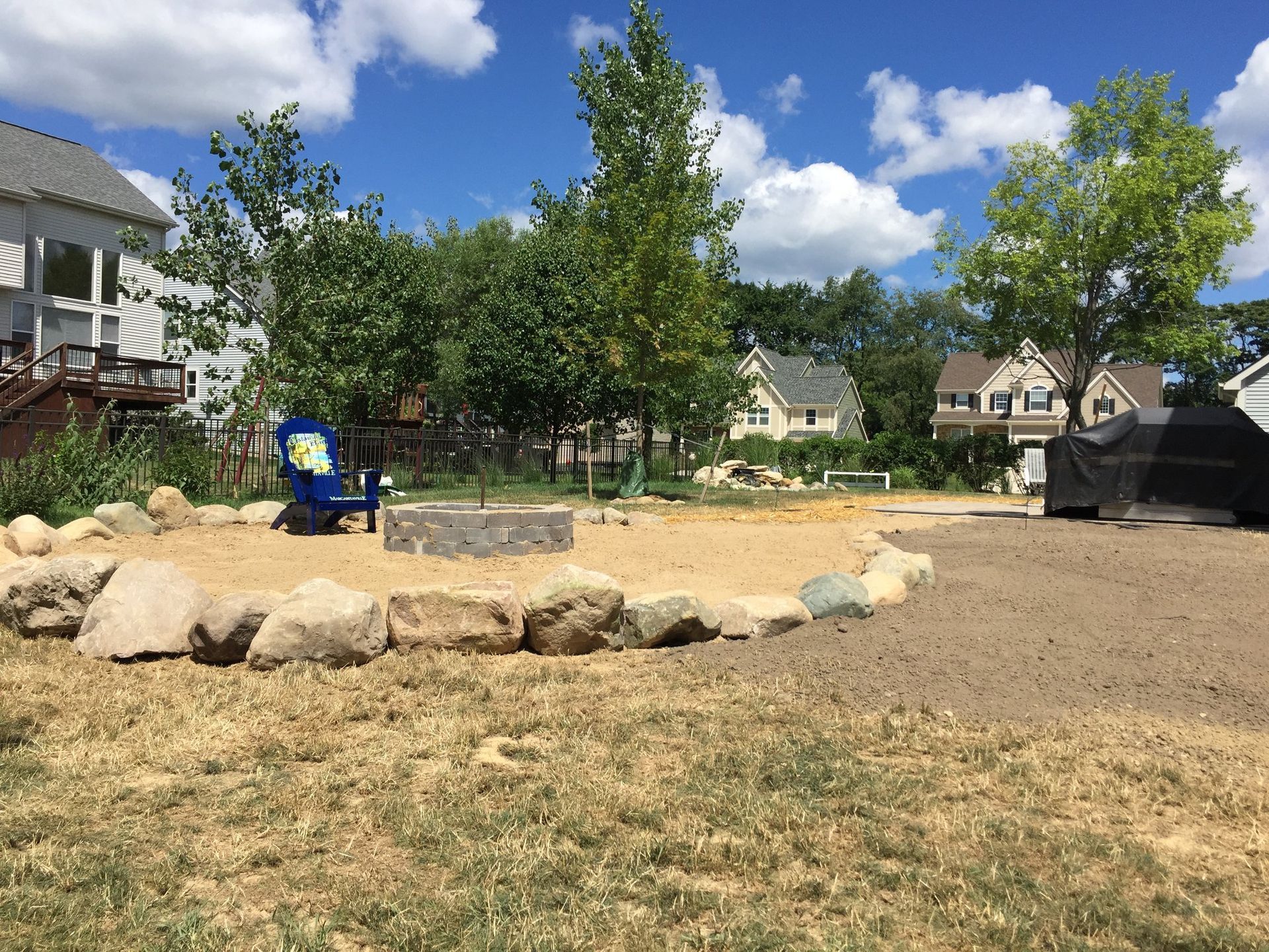 A blue chair is sitting in the middle of a grassy field.
