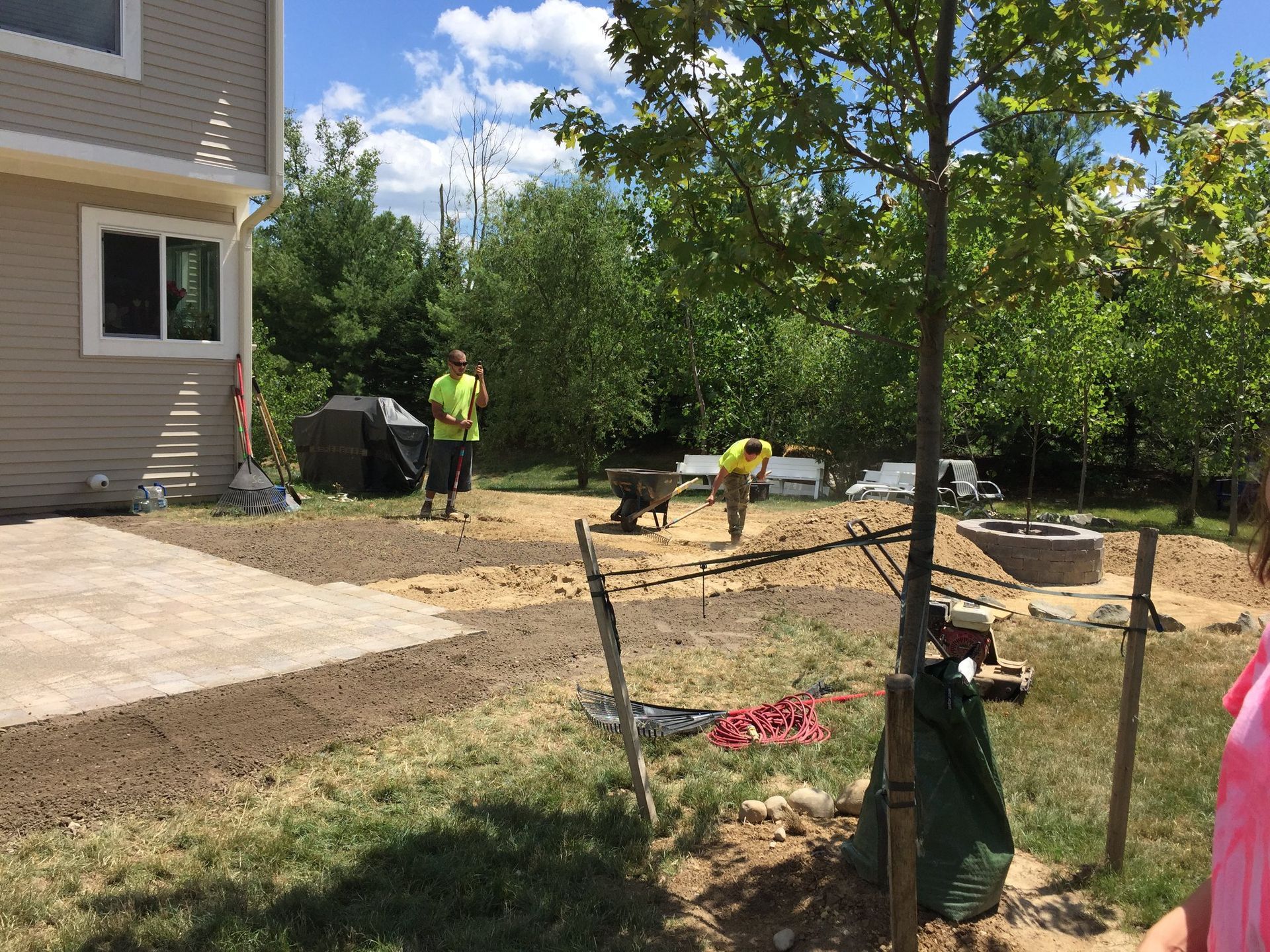 A group of people are working in a yard in front of a house.
