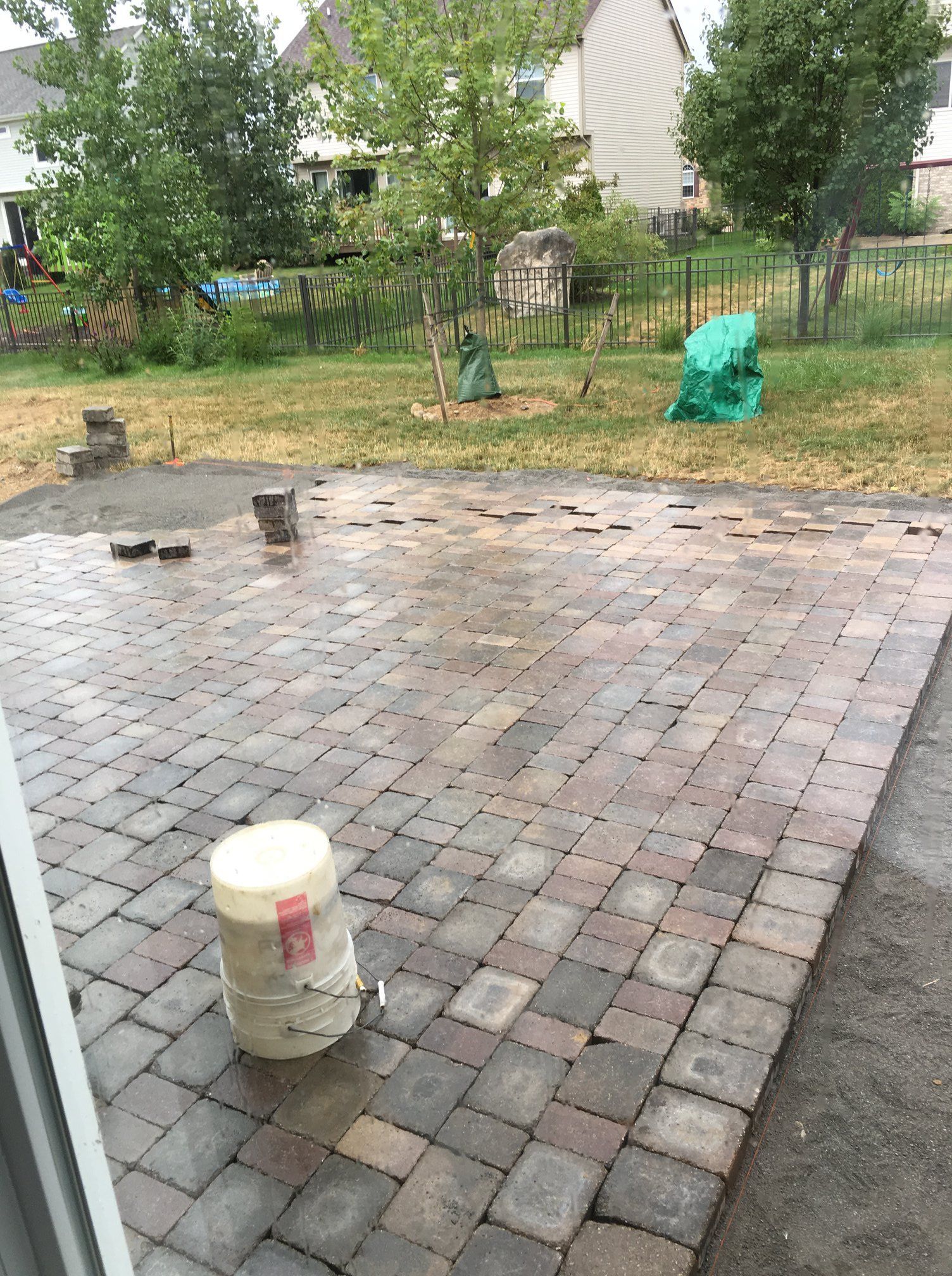 A bucket is sitting on top of a brick patio.