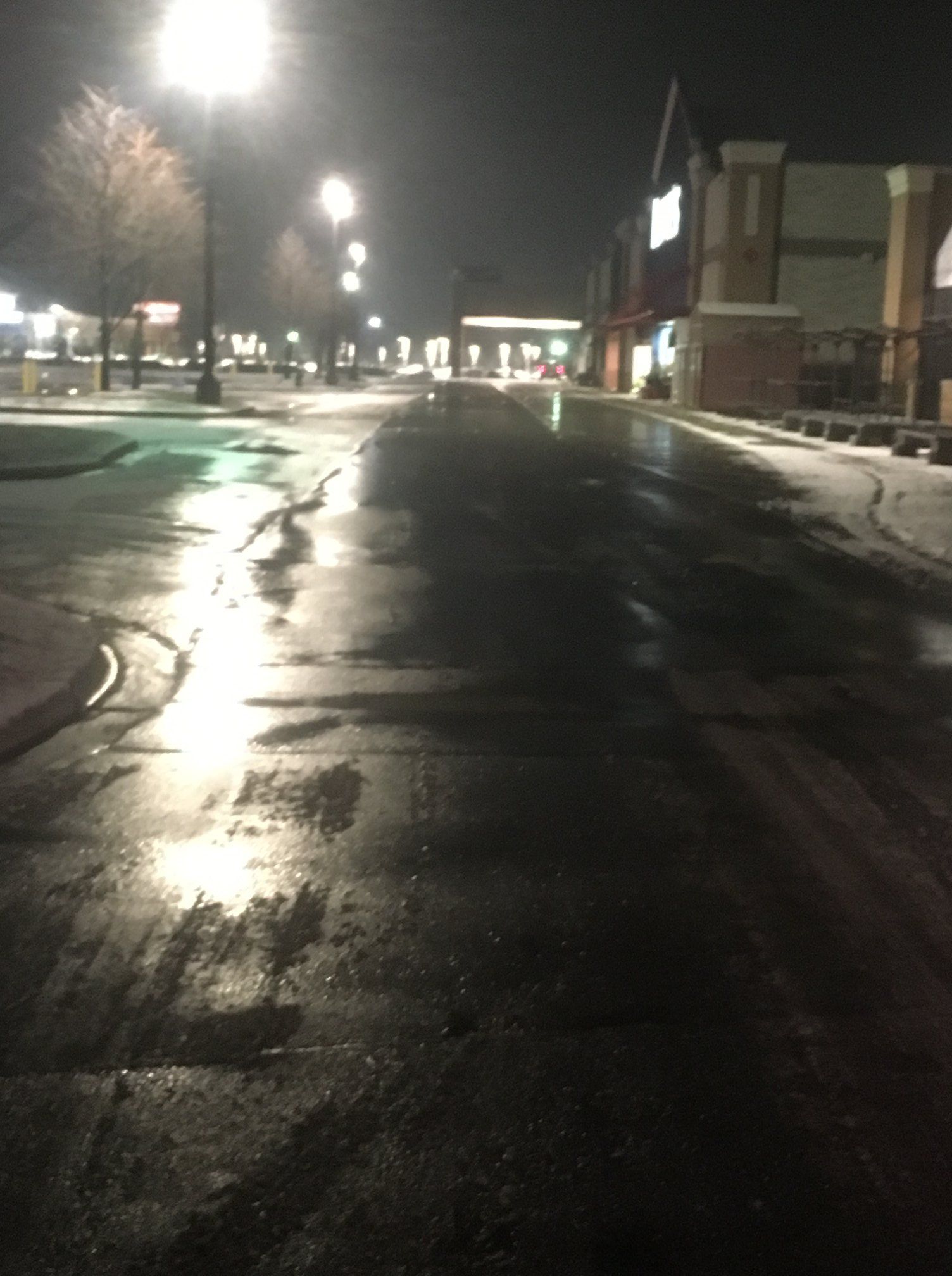 A dark street at night with a few lights on