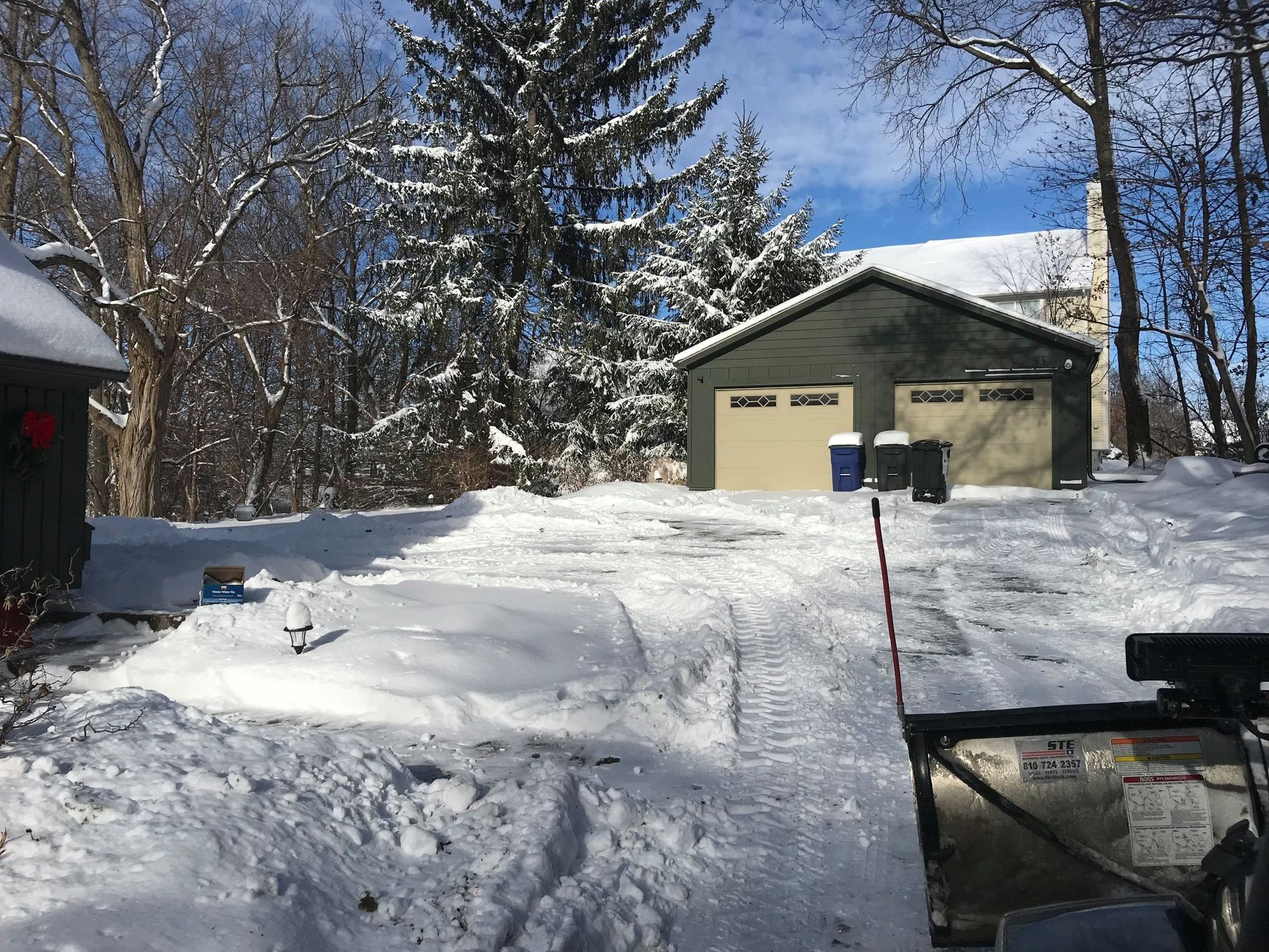 A snow blower is sitting in the snow in front of a house.