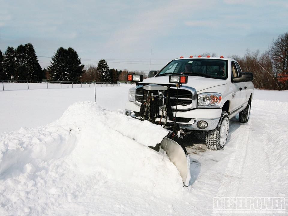 A snow plow is parked in front of a building at night.