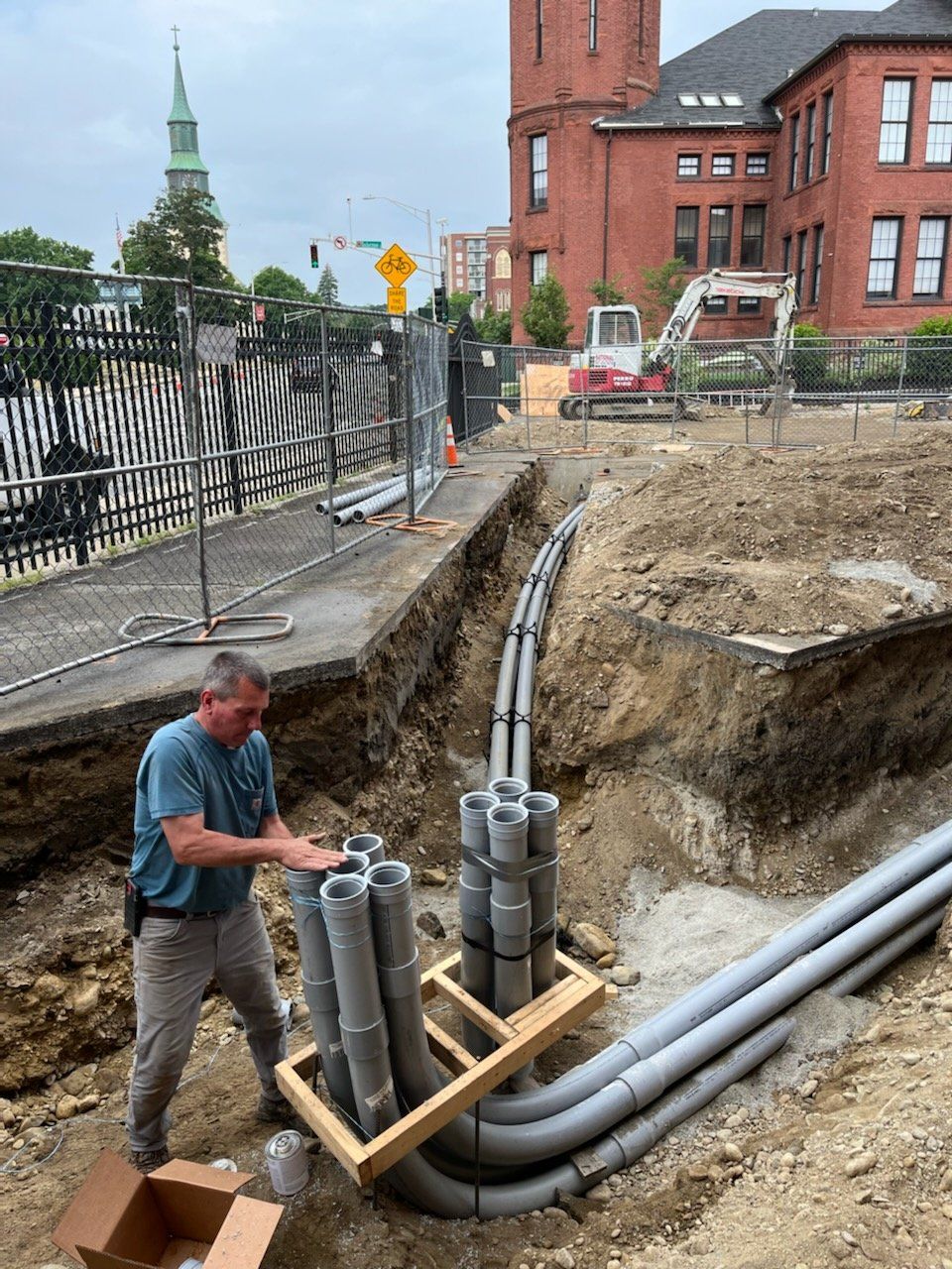 A man is standing in the dirt next to a bunch of pipes.