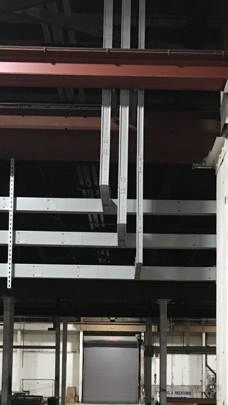 A warehouse with a lot of pipes hanging from the ceiling.