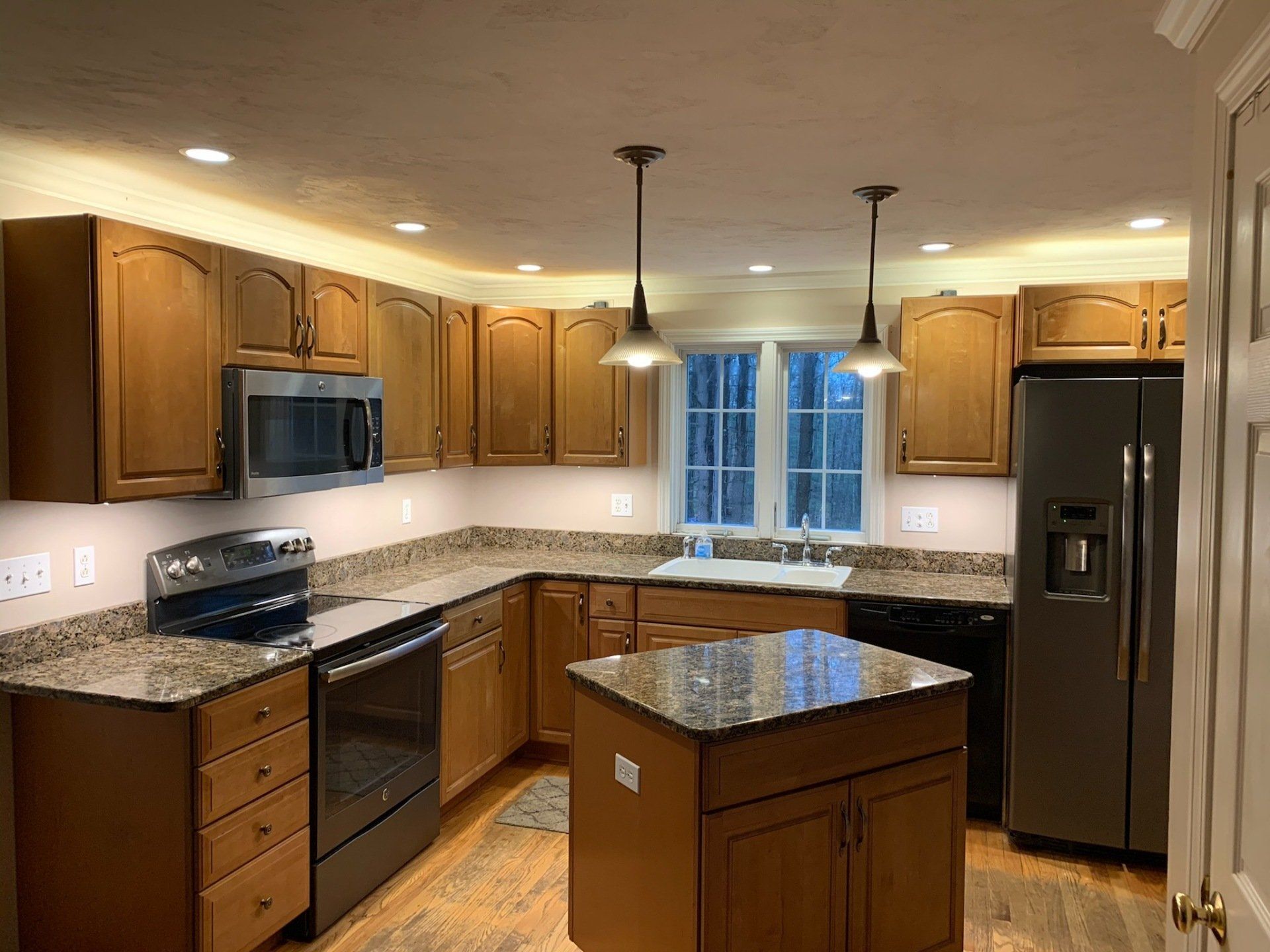 A kitchen with wooden cabinets , granite counter tops , stainless steel appliances and a large island.