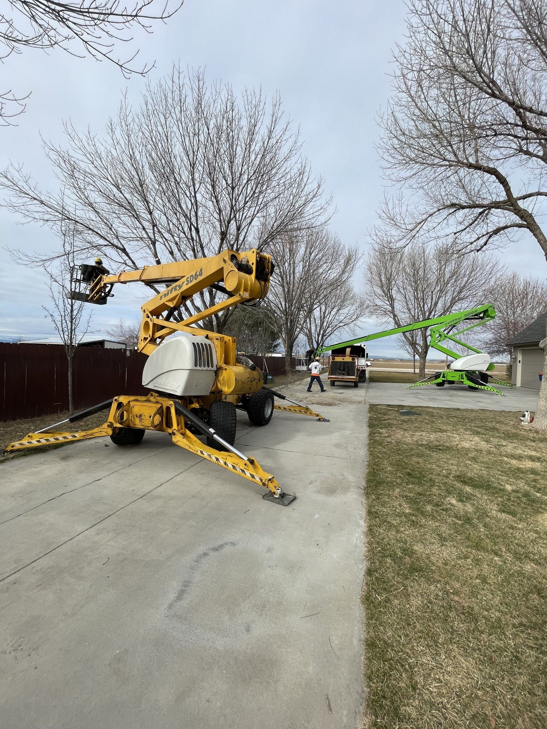 A yellow crane is sitting in a driveway next to a house.