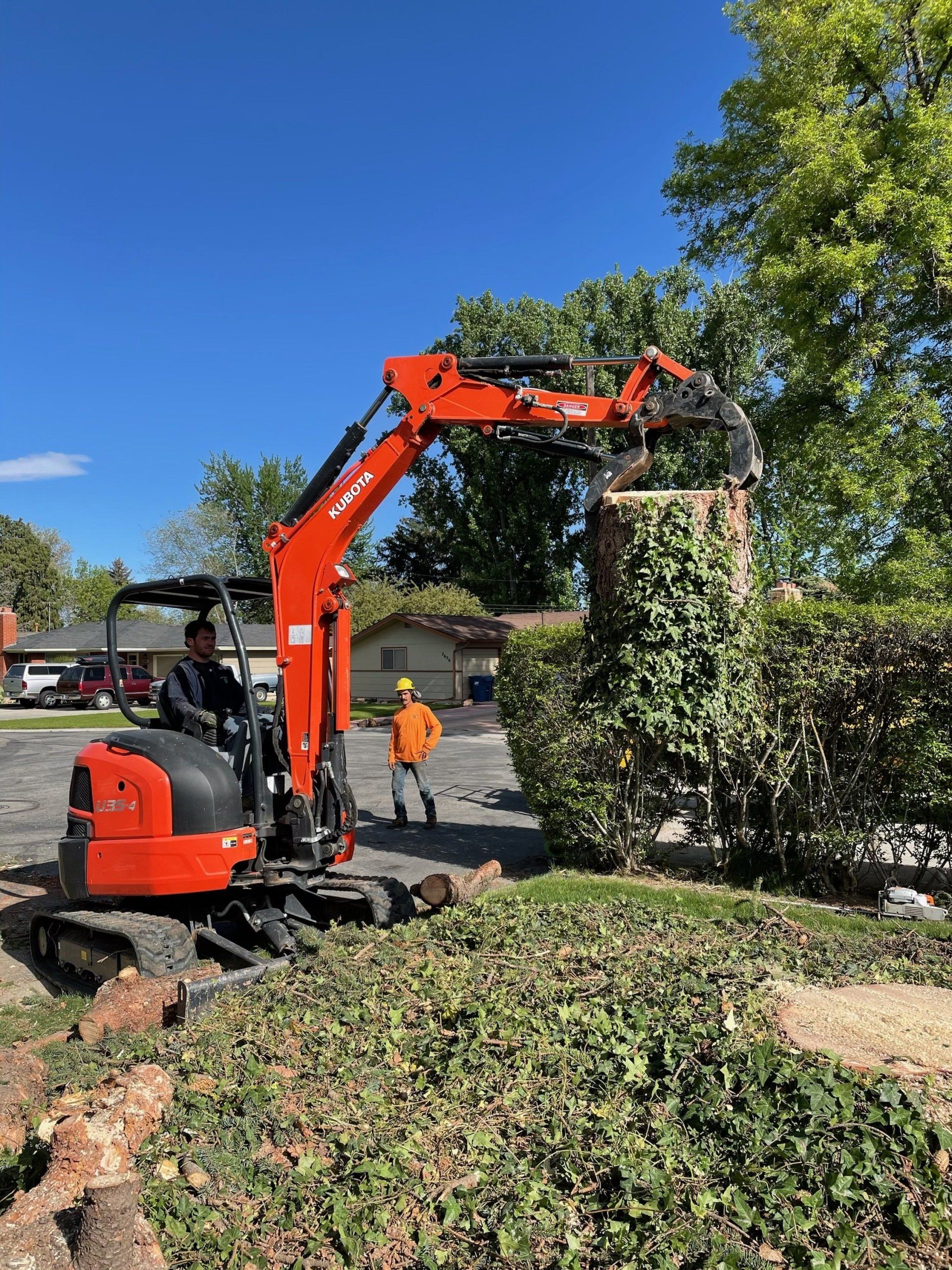 A man is driving a small excavator in a yard.