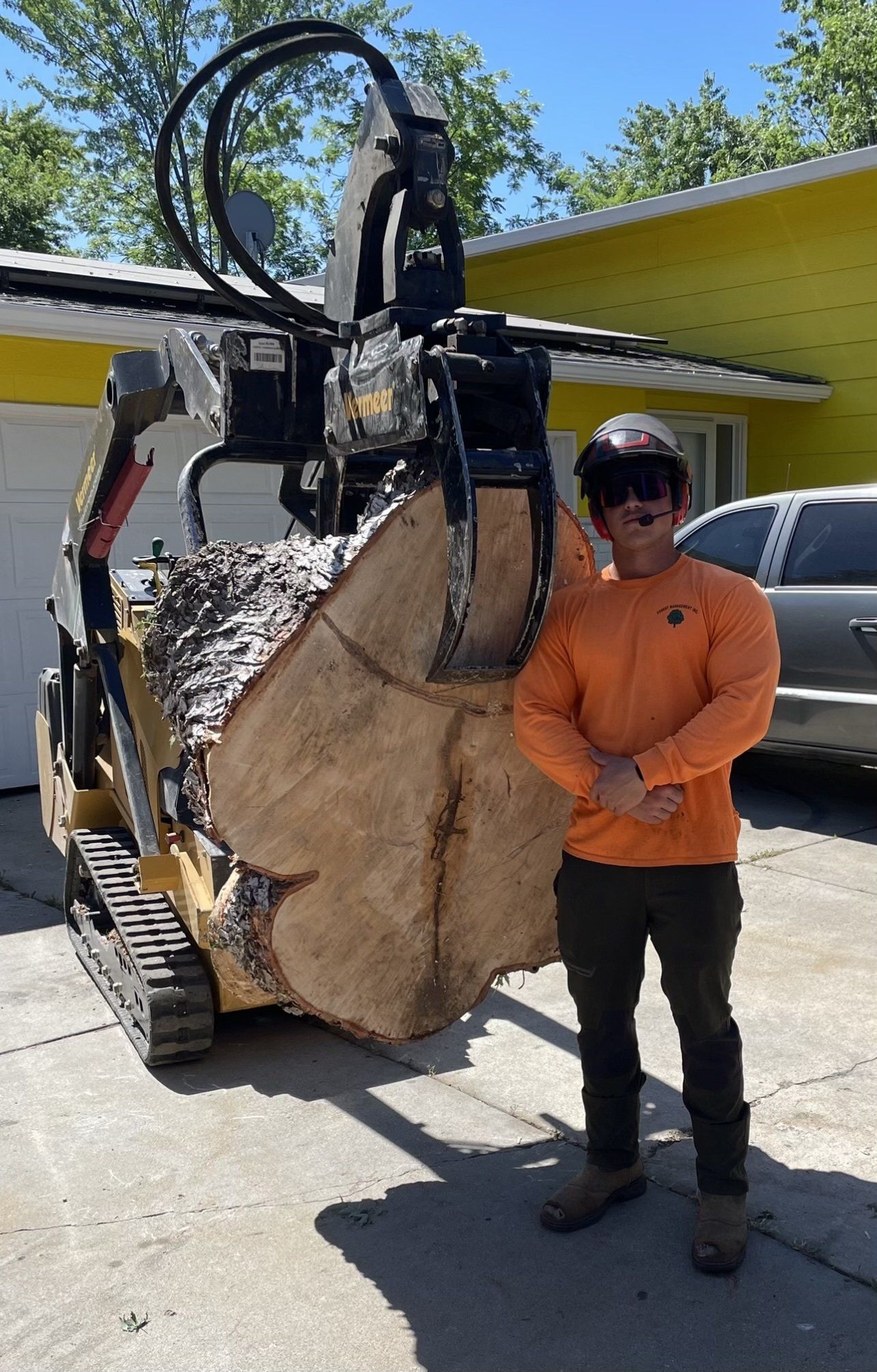 A man is standing next to a large piece of wood in front of a machine.