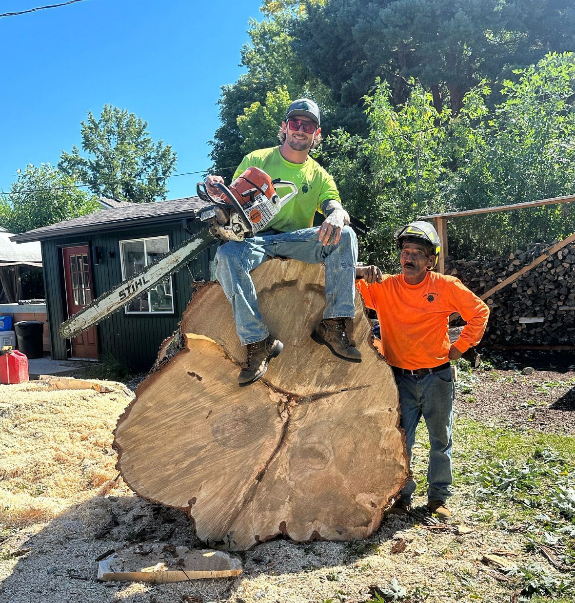 A man is sitting on a tree stump with a chainsaw.
