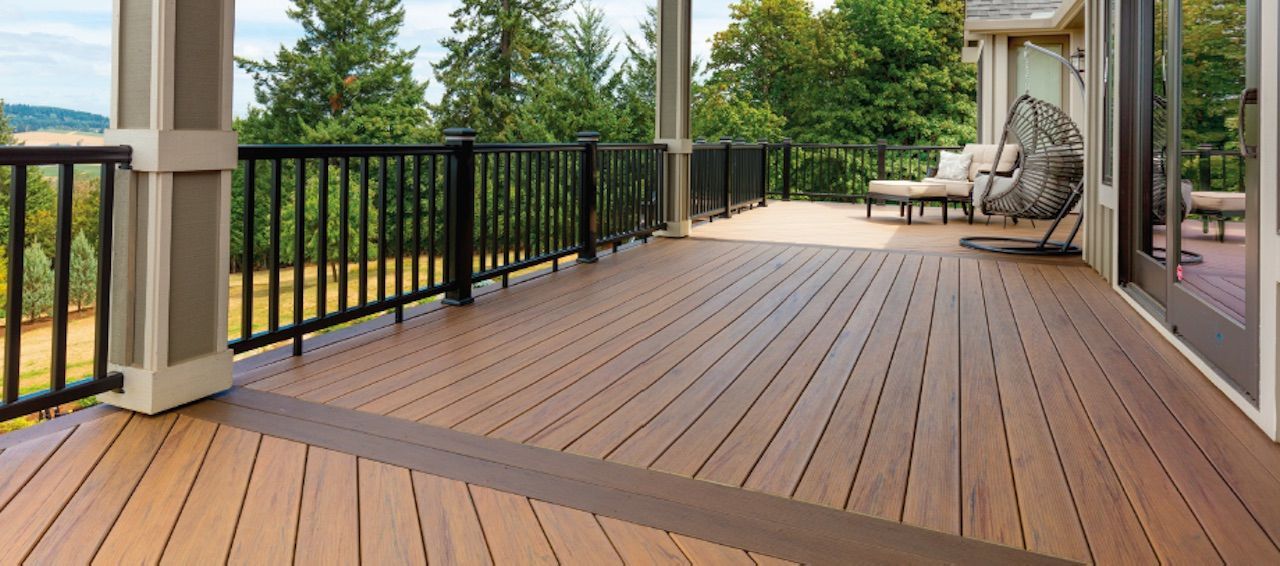A wooden deck with black railing and a surrounding nature view.