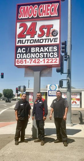 Three men are standing in front of a smog check sign