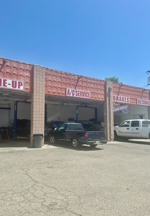 A truck is parked in front of a car repair shop.
