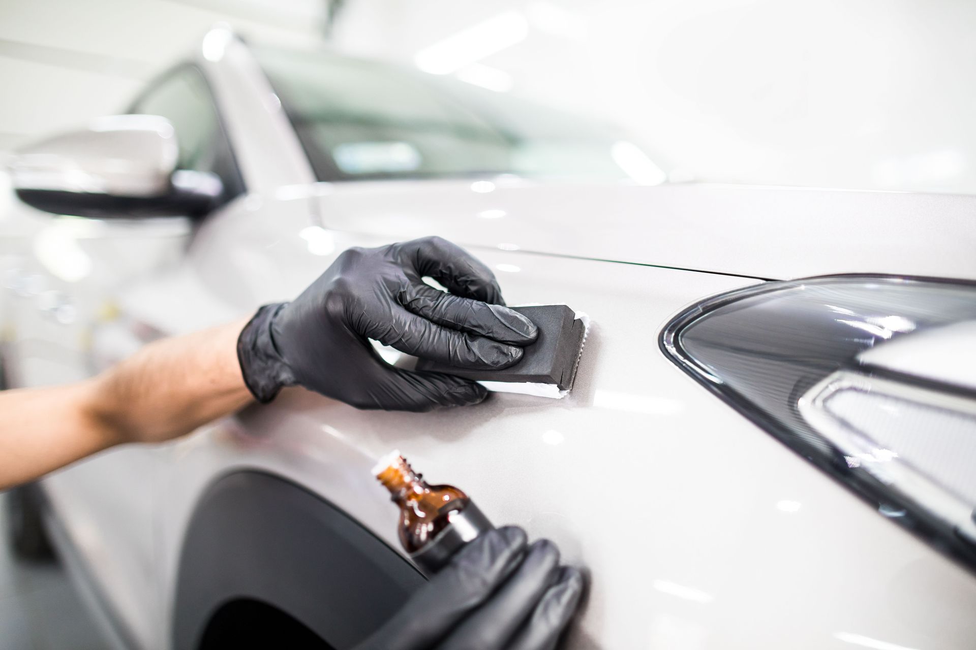 A person is applying ceramic coating to a white car.