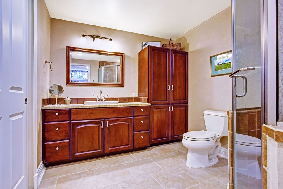 Spacious bathroom with wood vanity, mirror, toilet, and glass shower enclosure