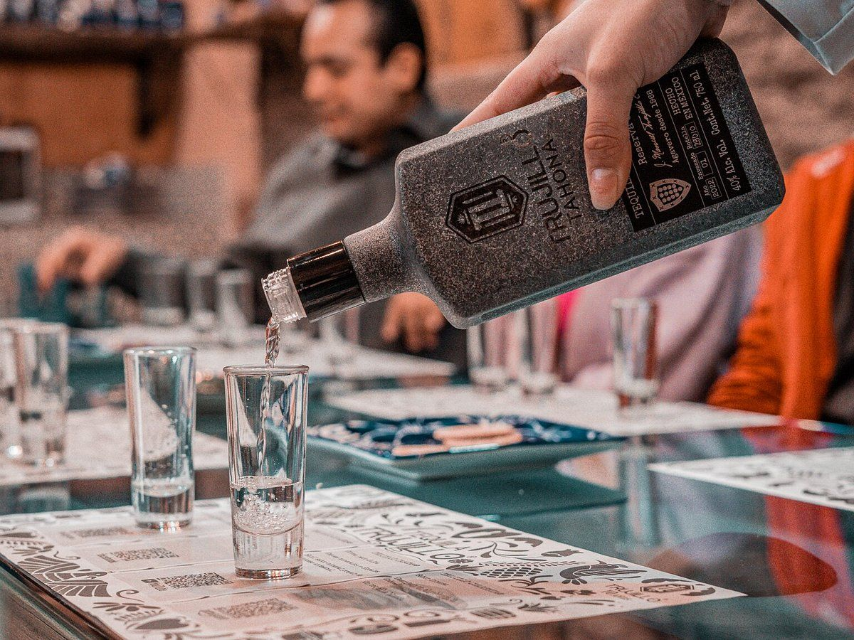 A man is standing in front of a building with a bicycle and a glass of wine.
