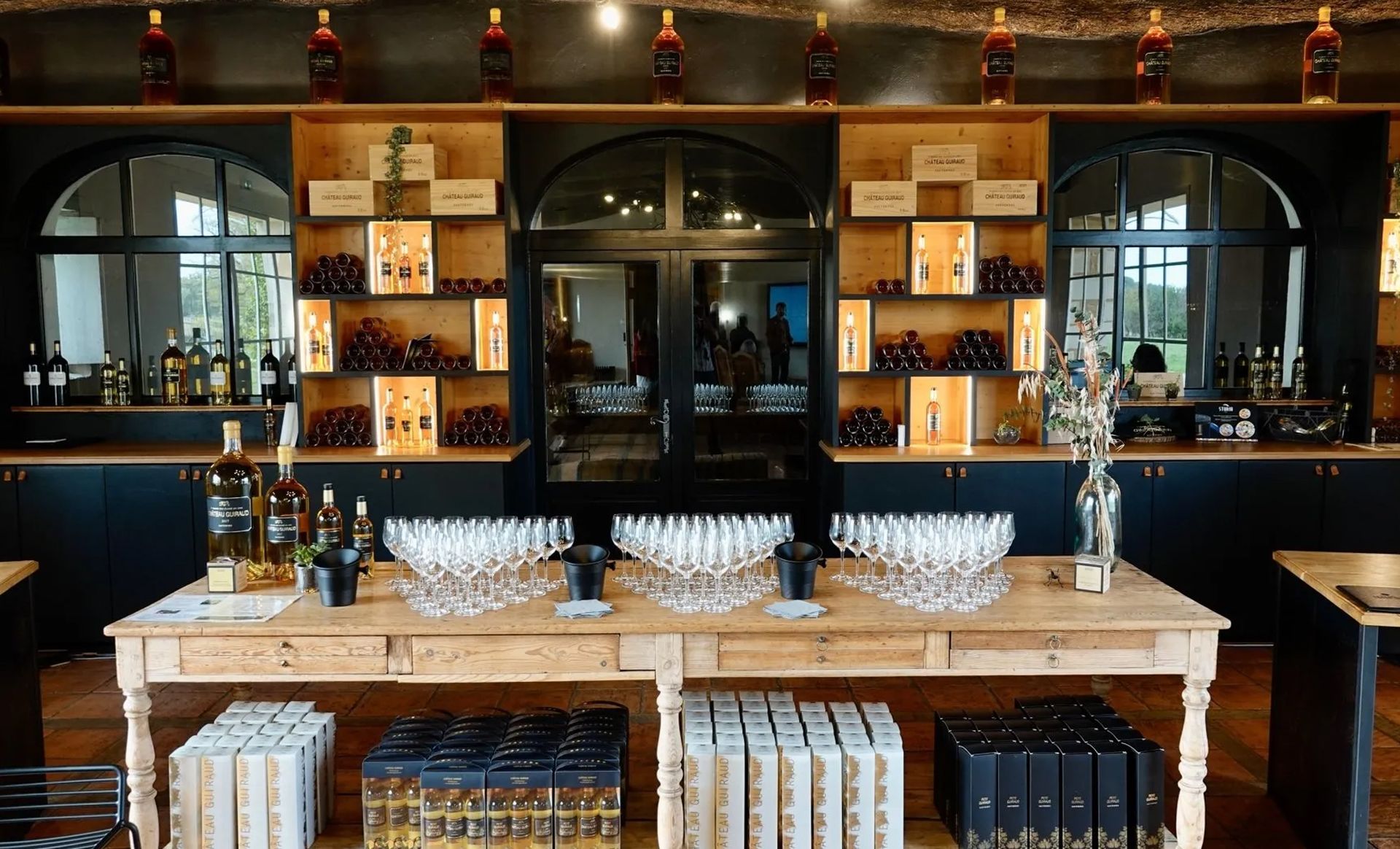 A large room filled with lots of bottles and glasses on a table.