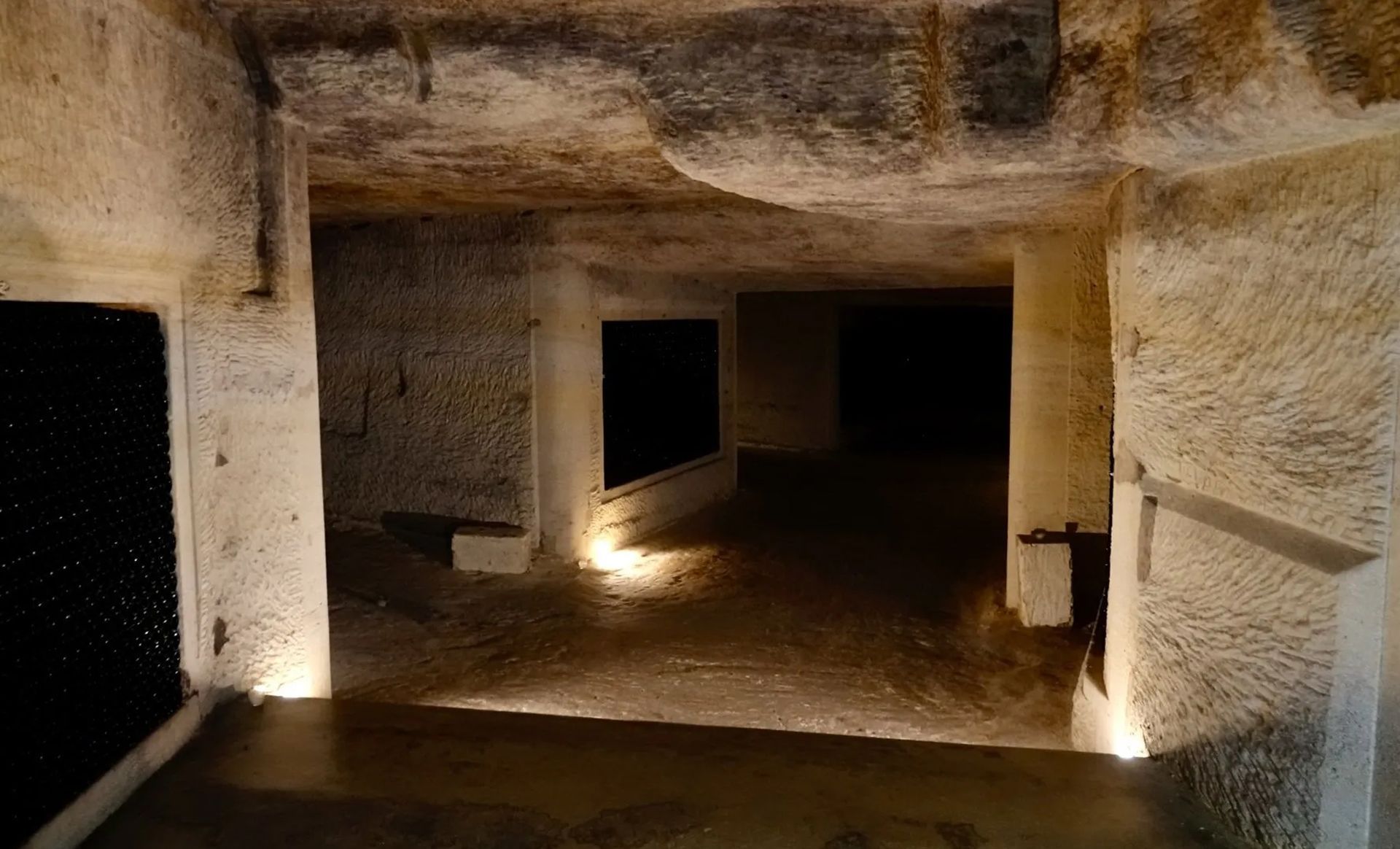 A dark cave with a few lights on the walls and floor.