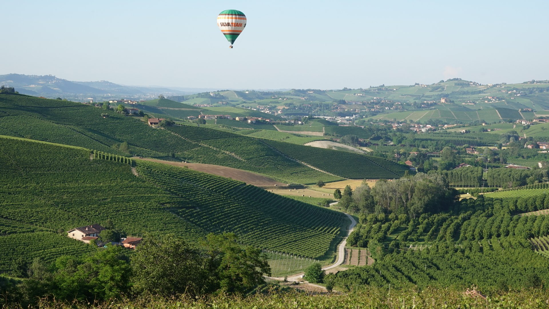 A hot air balloon is flying over a lush green valley.
