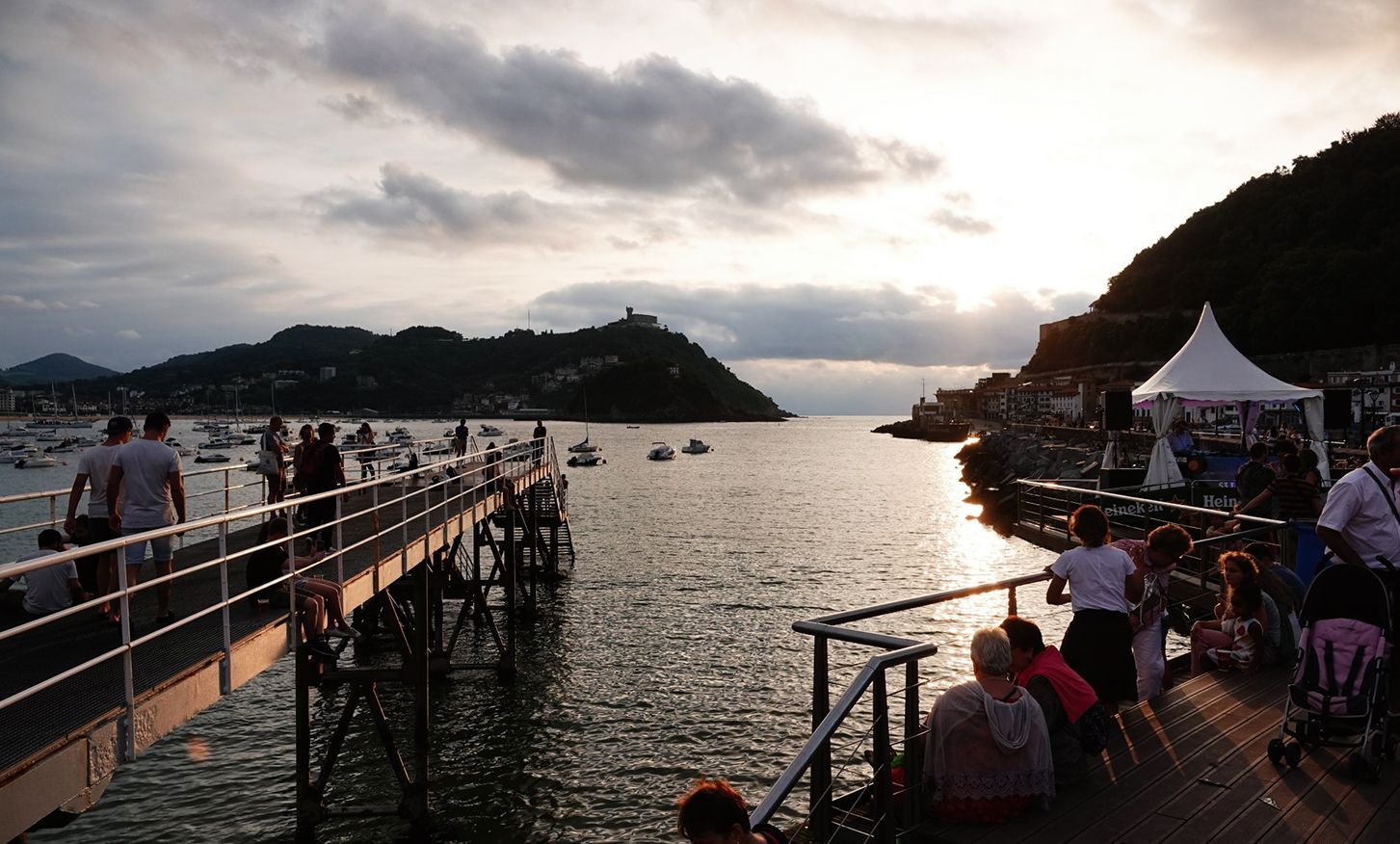 A group of people standing on a pier overlooking a body of water