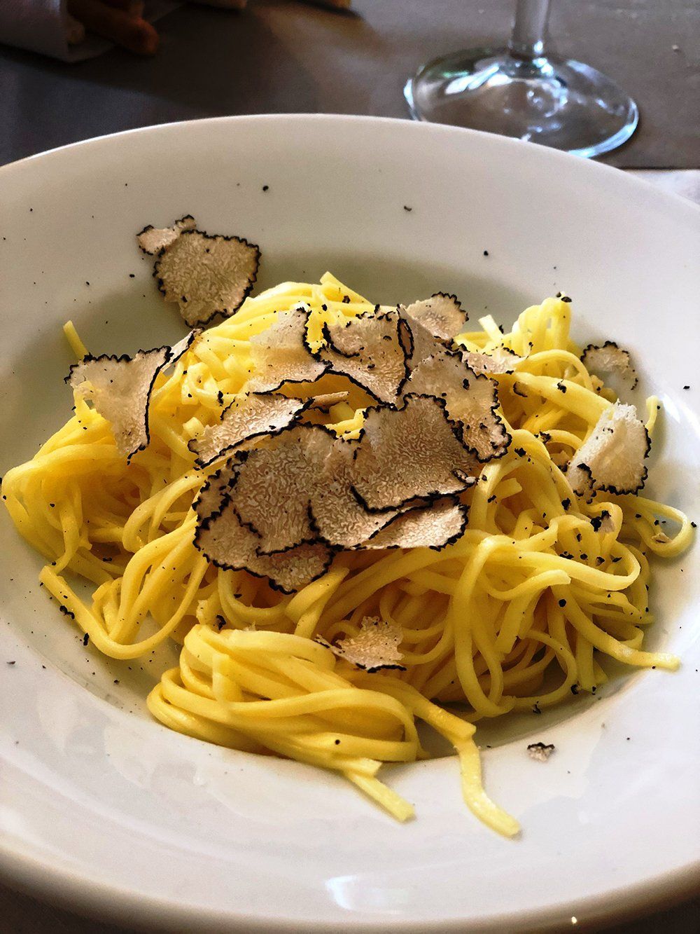 A white plate topped with noodles and truffle slices