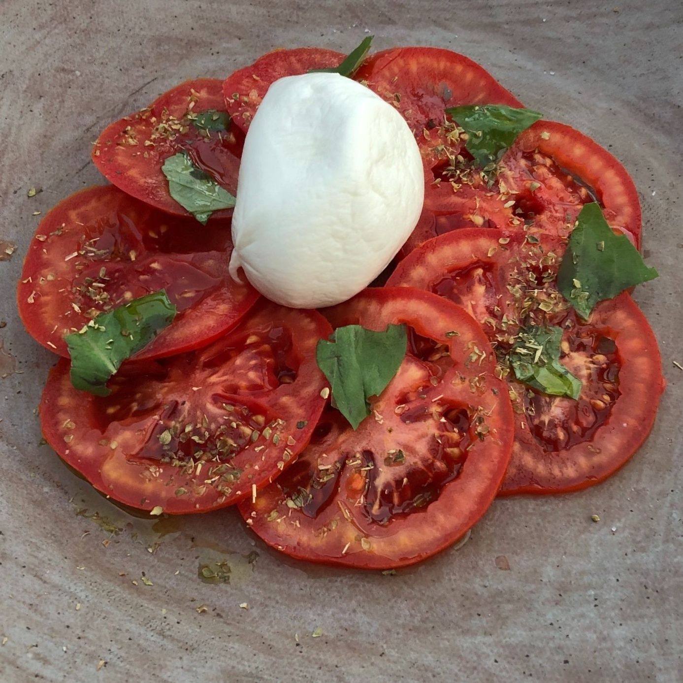A plate of sliced tomatoes with mozzarella on top