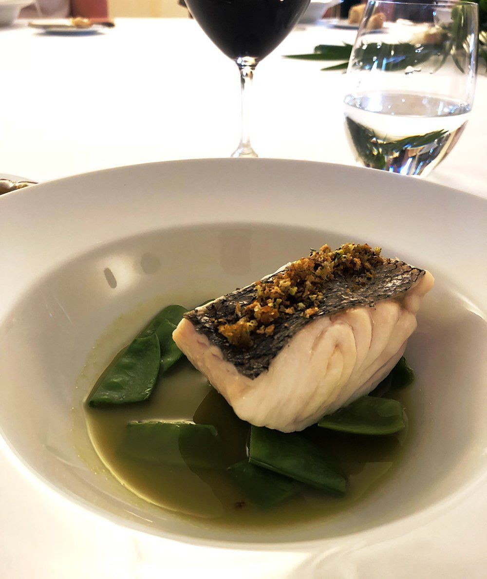 A plate of food with a glass of wine in the background