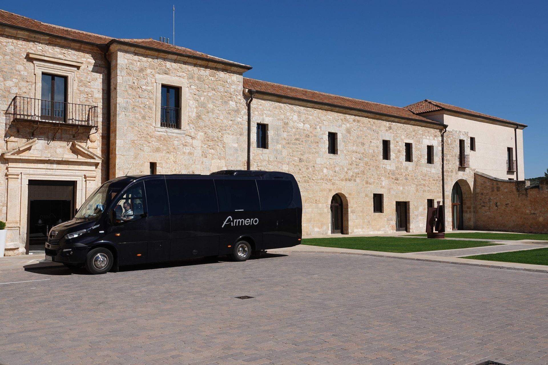 A black van is parked in front of a stone building