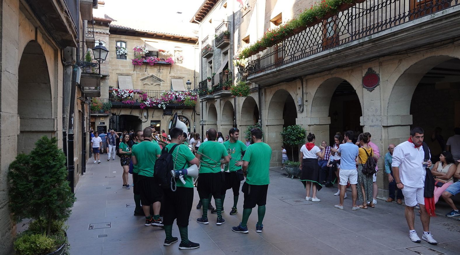 A group of people in green shirts are walking down a street.