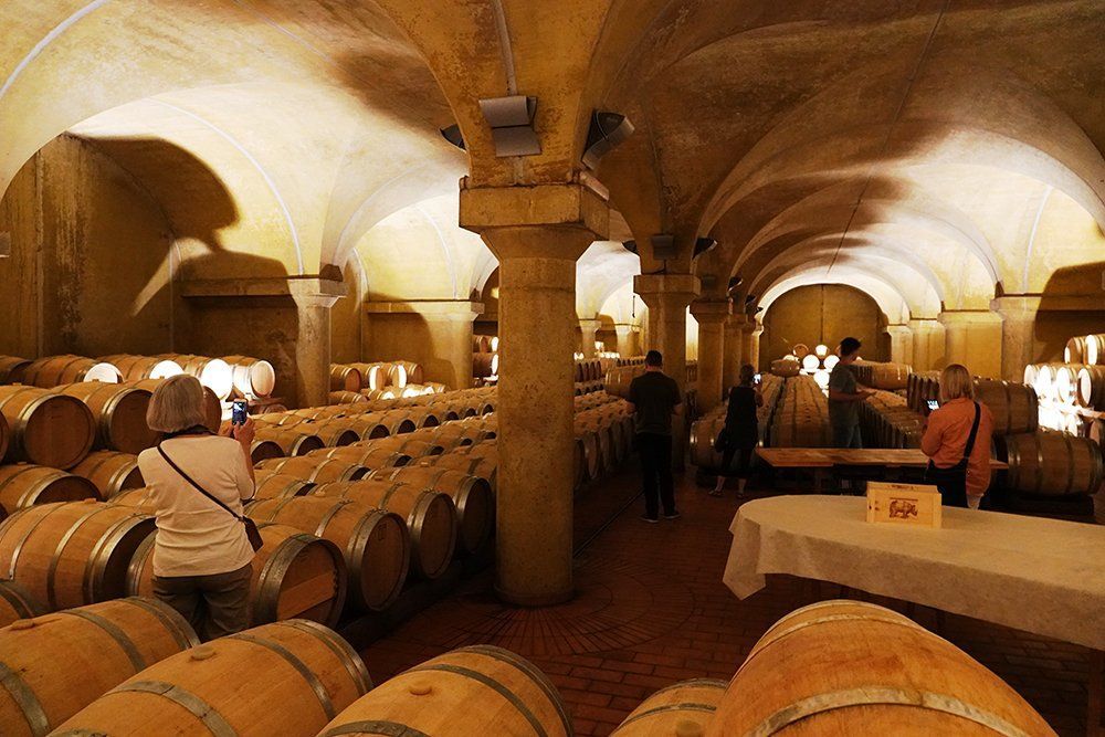 A wine cellar filled with lots of barrels and people