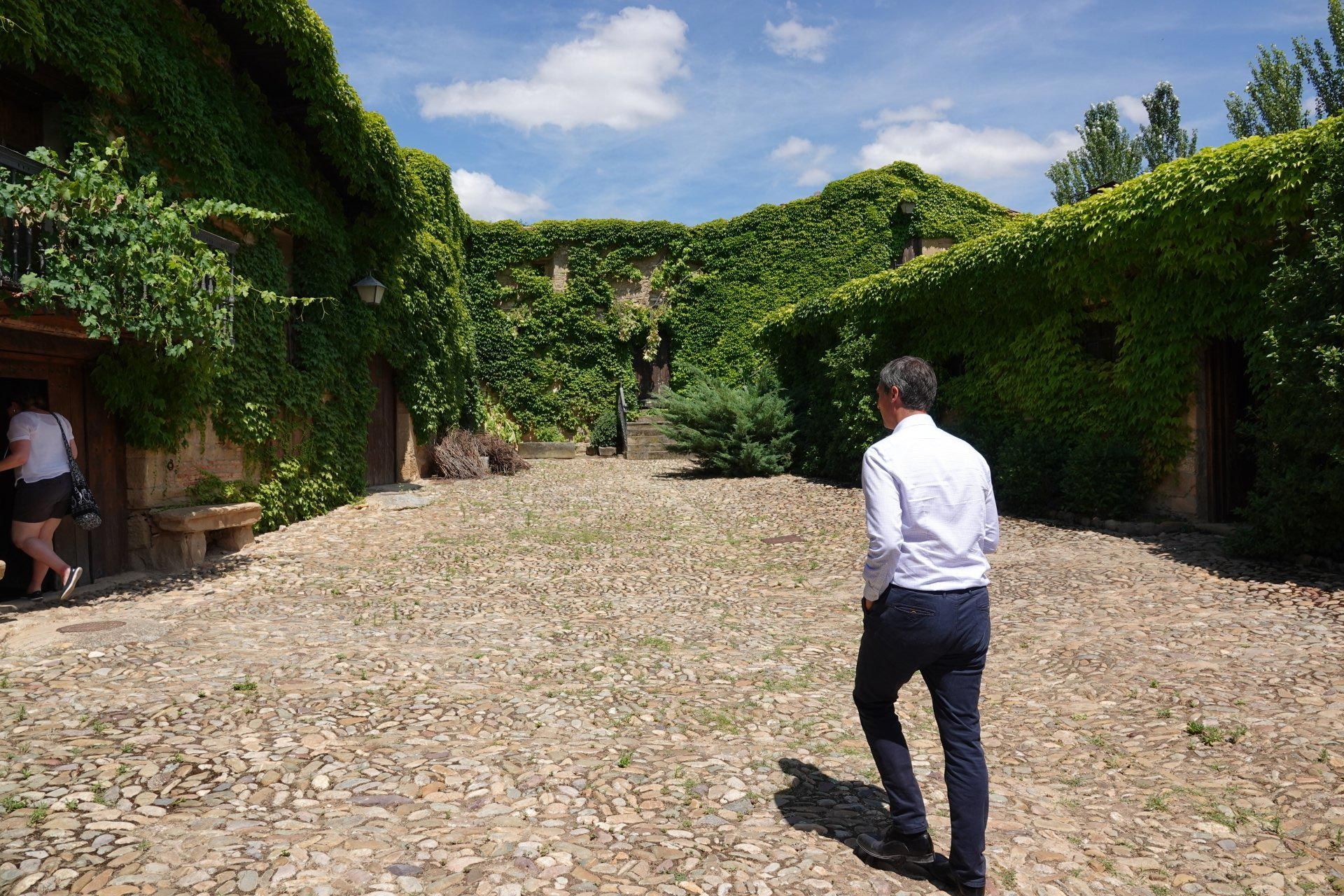 A man in a white shirt is walking down a cobblestone road