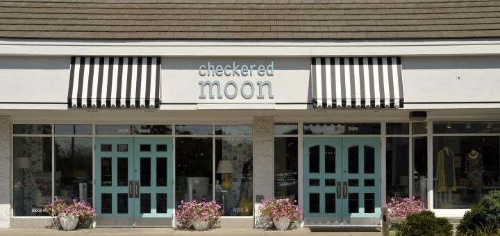 Exterior of a store with blue doors and black and white striped awnings that reads