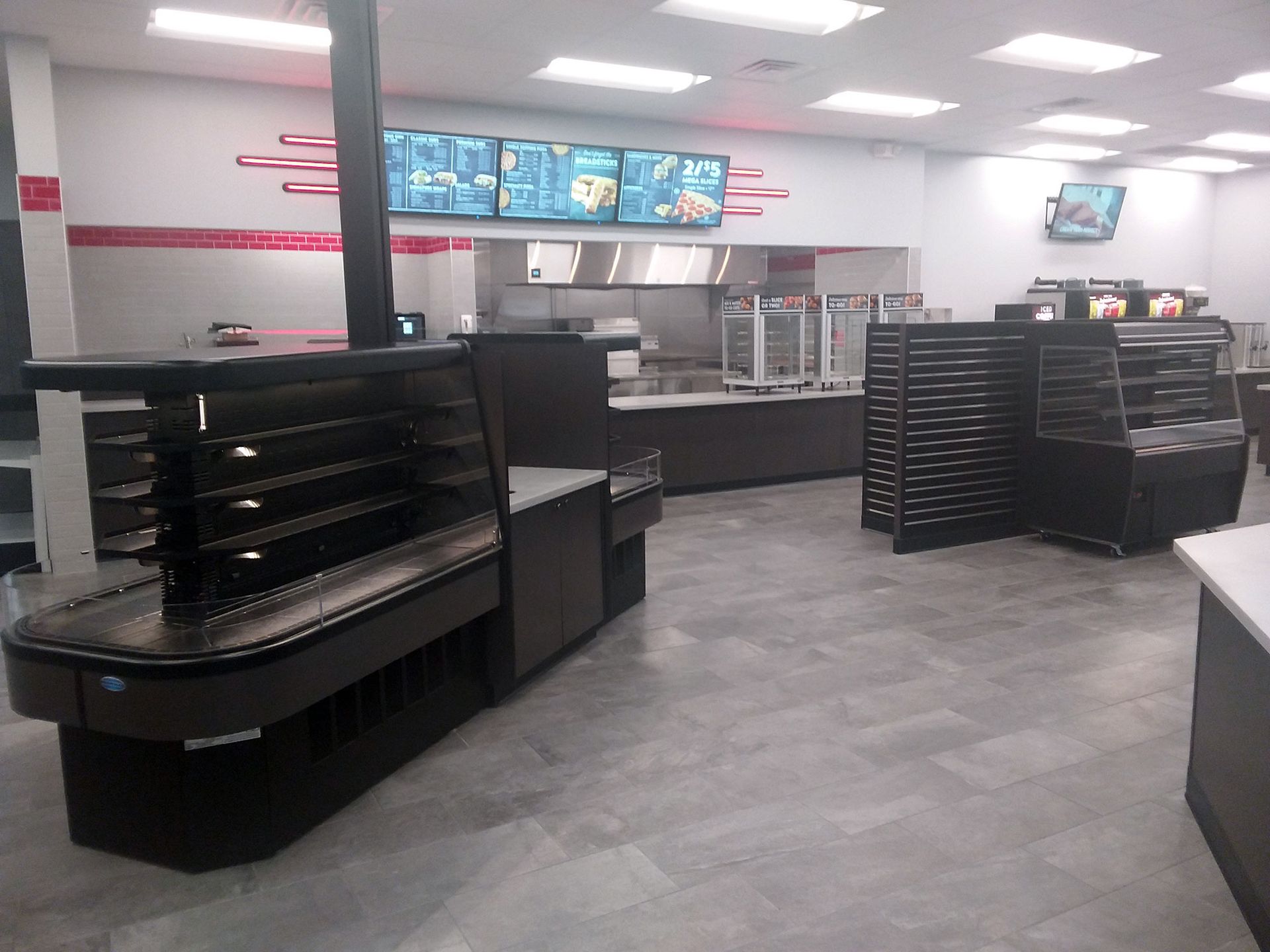 Empty interior of a food service business with serving counters, display cases, and menu boards.