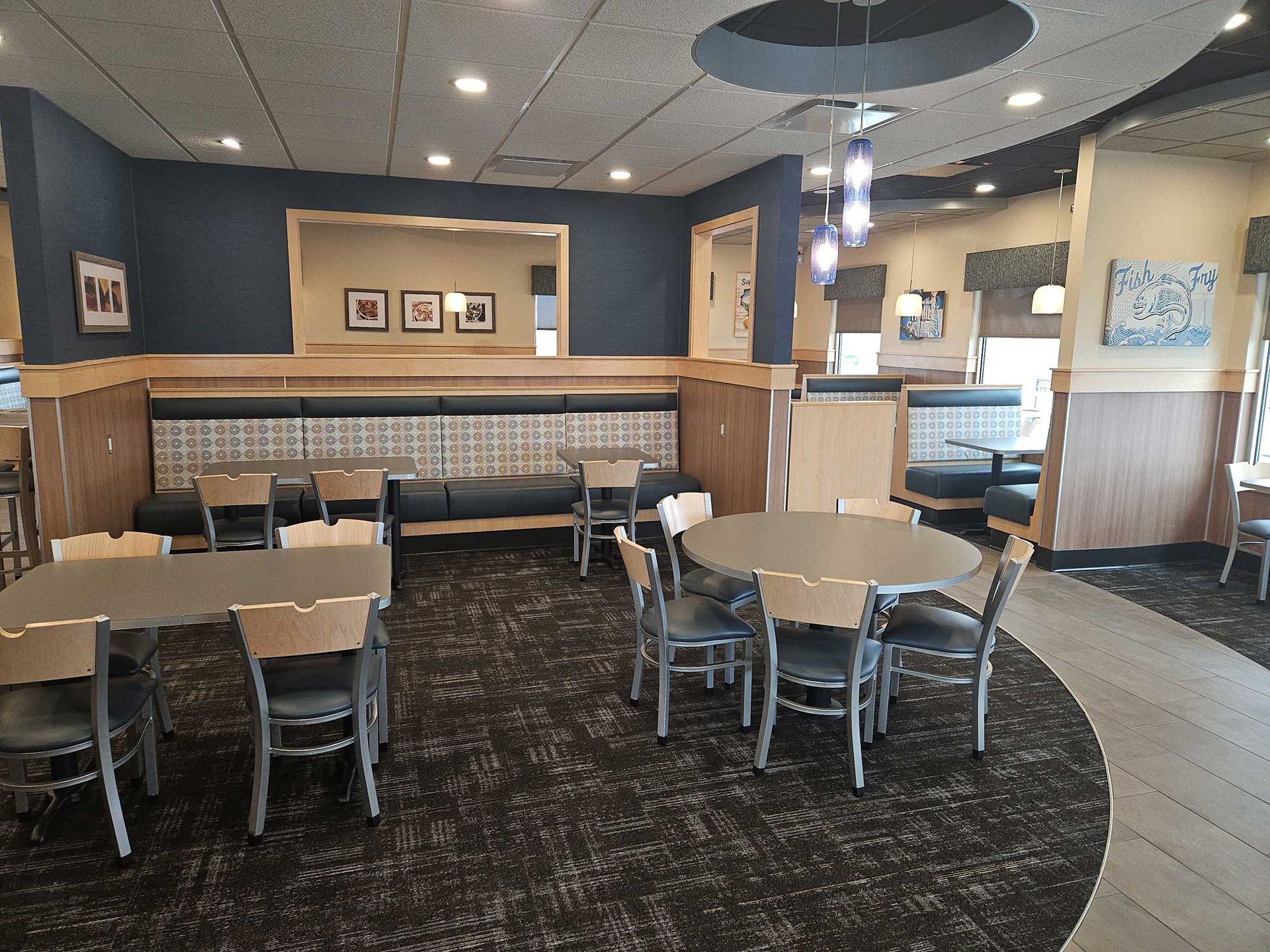 Interior of a restaurant with tables, chairs, booths, and a dark blue accent wall.