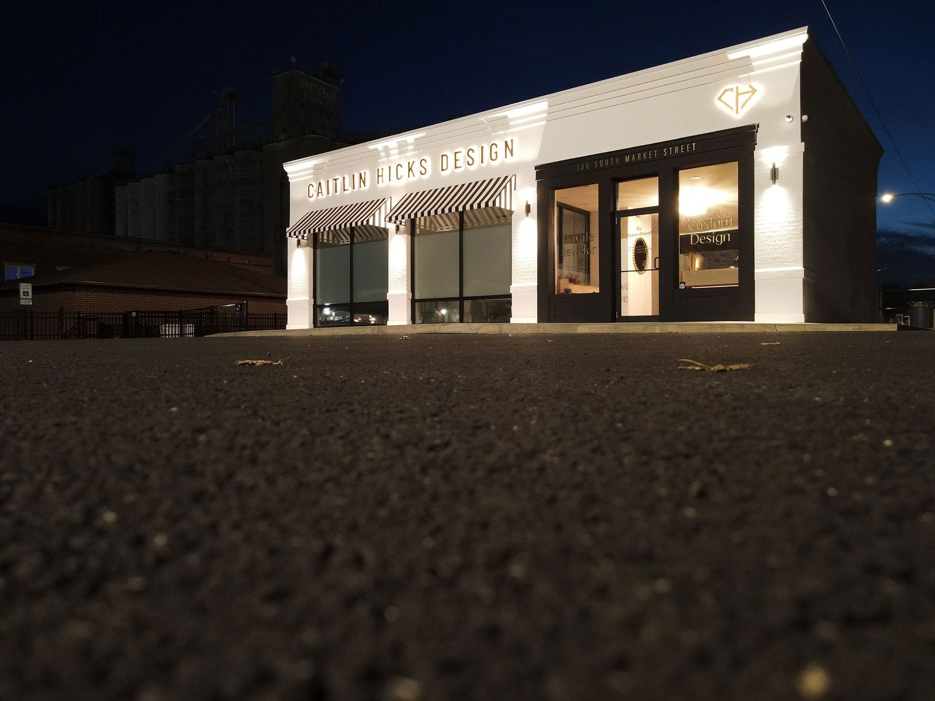 White building with storefront at dusk; sign reads 