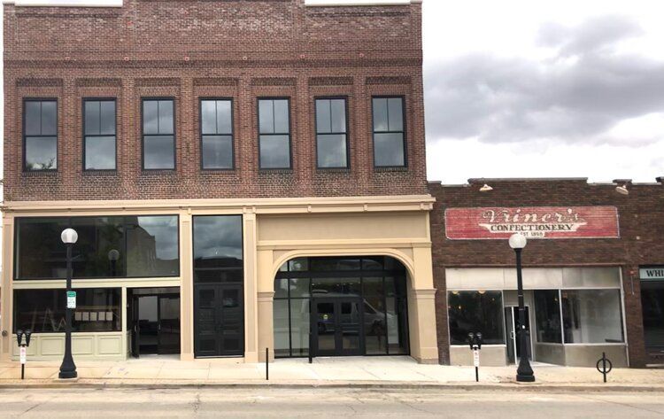 Brick buildings with large glass windows and entryways, street view.