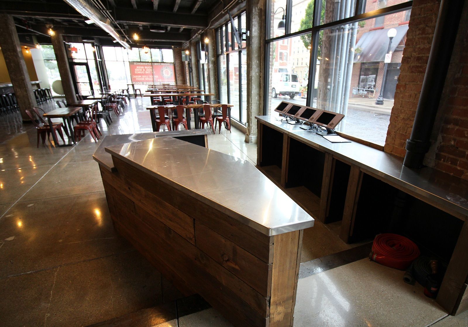 Interior of a modern cafe: wood and metal counter, tables, large windows looking onto a street.