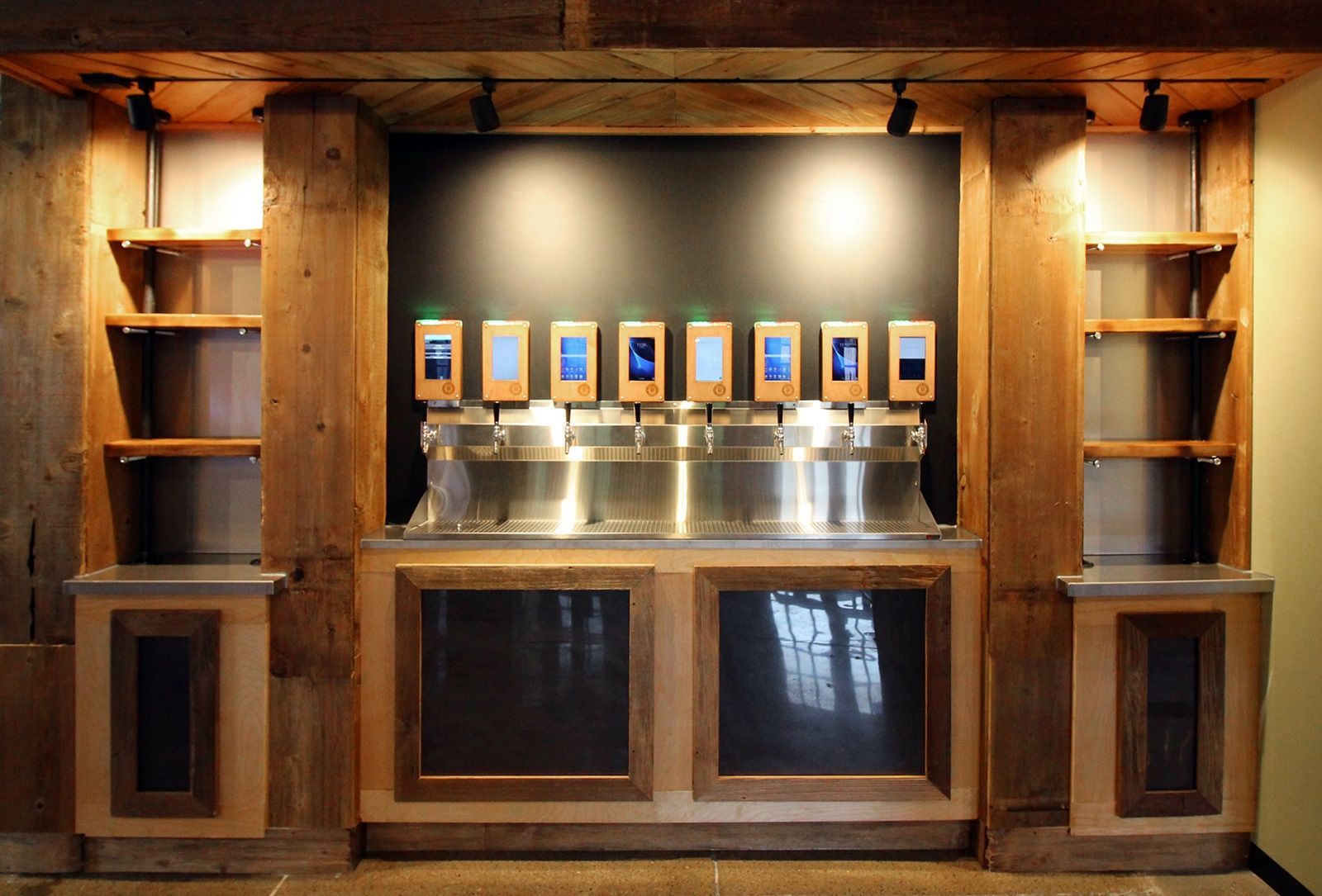 Bar with multiple drink dispensers and shelves, built-in wooden structure.
