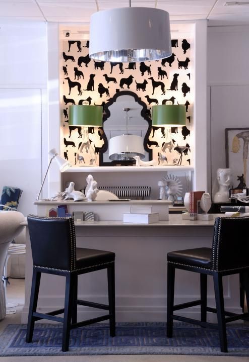 Bar area with black stools, dog silhouette wallpaper, and green lamp shades.