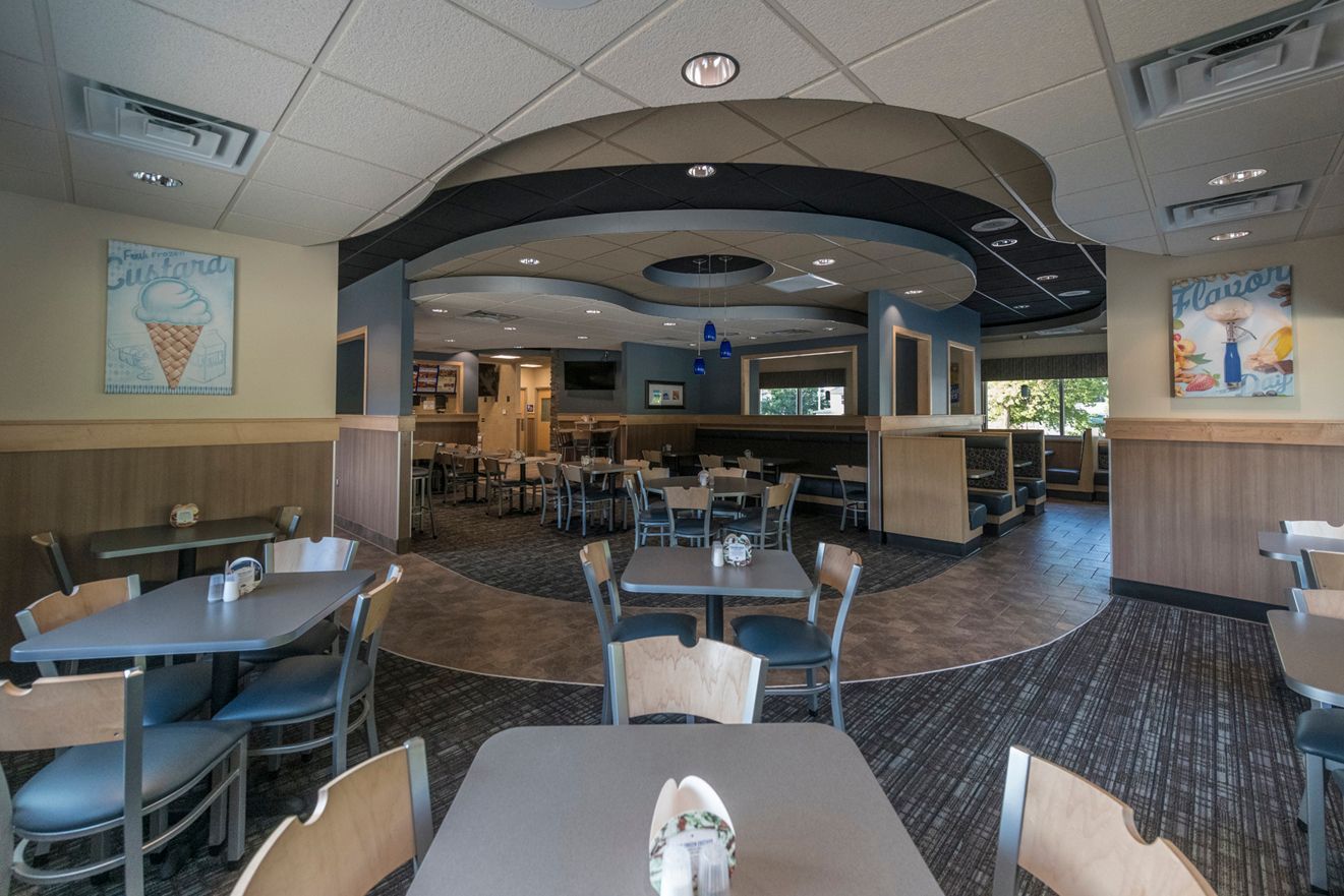Interior of a restaurant with tables, chairs, and artwork on the walls.